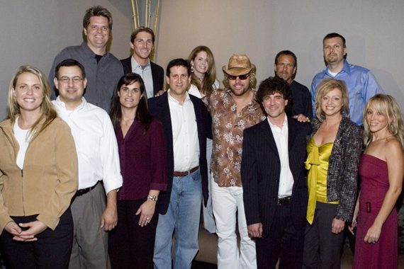 An August 31, 2005 press conference where Scott Borchetta and Toby Keith announced two business entities equally share the same staffing resources—Keith’s Show Dog and Borchetta’s Big Machine. Pictured (L-R): Front: Darcy Miller-Lashinsky (Secondary Promotion/Promotion Coordinator), Tony Morreale (Southeast Promotion & Marketing), Lisa Owen (West Coast Promotion & Marketing), Zach Horowitz (President and Chief Operating Officer of Universal Music Group), Toby Keith, Scott Borchetta (President - Big Machine Records), Denise Roberts (VP/Promotions) , Sandi Spika-Borchetta (Creative Services); Back: Greg Sax (Southwest Promotion & Marketing), John Zarling (National Promotions & New Media), Suzanne Durham (Northeast Promotion & Marketing), George Nunes (GM/Show Dog), Andrew Kautz (Controller/Office Manager)
